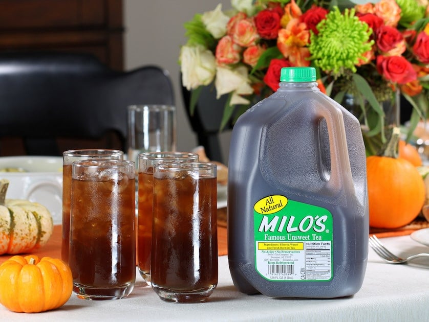 Four glasses of iced tea on a table with a jug of iced tea