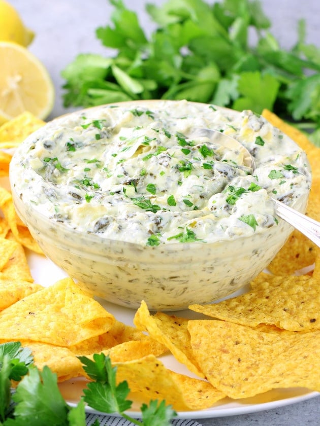 A bowl of artichoke spinach dip on a platter