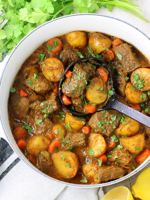 A bowl filled with meat and vegetables, with Beef and Potato Curry.