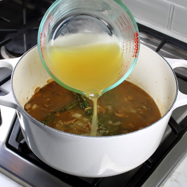 Adding chicken stock to large white pot