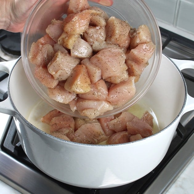 Adding raw chicken to dutch oven on stovetop
