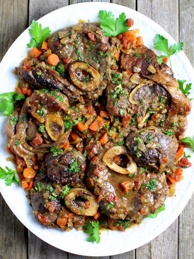 Veal Osso Buco on a white platter with parsley garnish