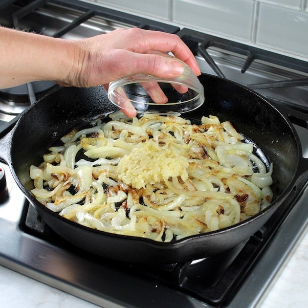 Adding garlic to cooked onions in a skillet