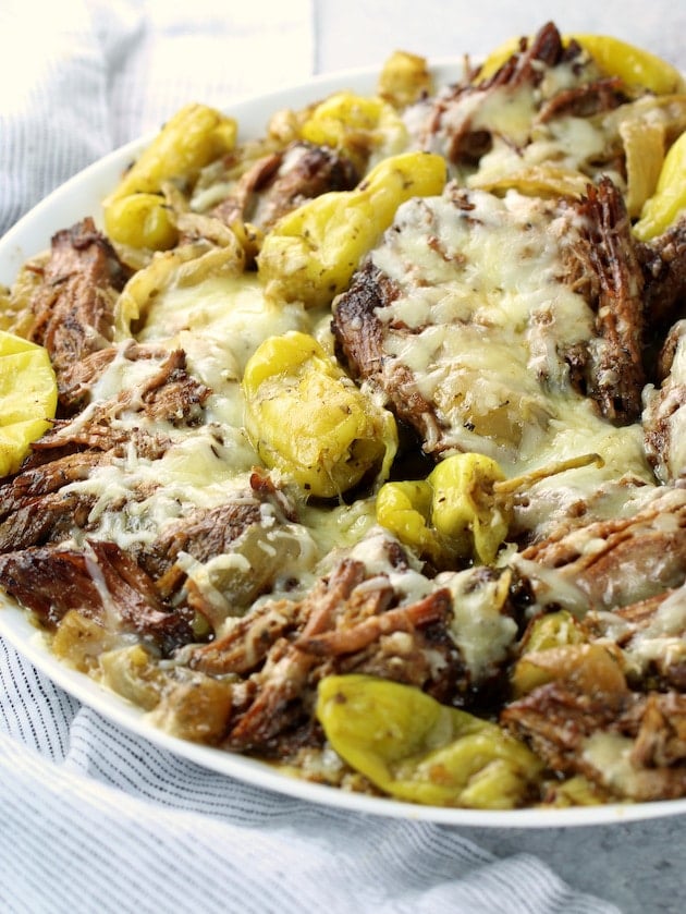 Partial platter of pulled slow cooker Italian beef with onions and pepperoncini