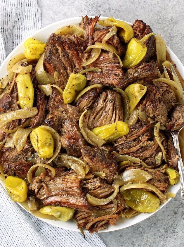 platter of pulled slow cooker Italian beef with onions and pepperoncini