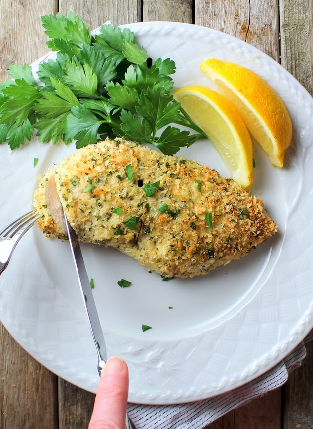 Parmesan Crusted Chicken on a plate with lemons &amp; parsley