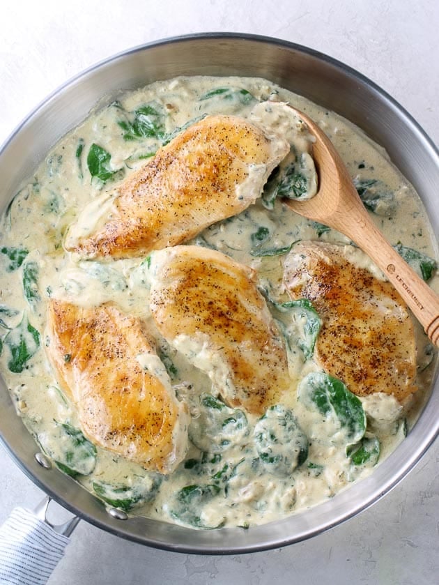 Whole chicken breasts in sauce with fresh spinach 