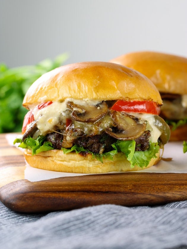 A close up of a cheeseburger sitting on top of a wooden cutting board