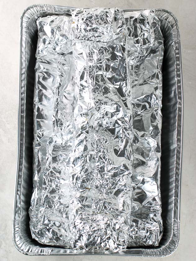 Three racks of ribs wrapped in tin foil for slow cooking