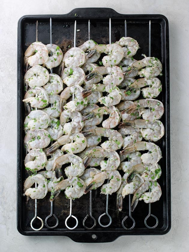 7 skewers of shrimp on a baking sheet ready to grill