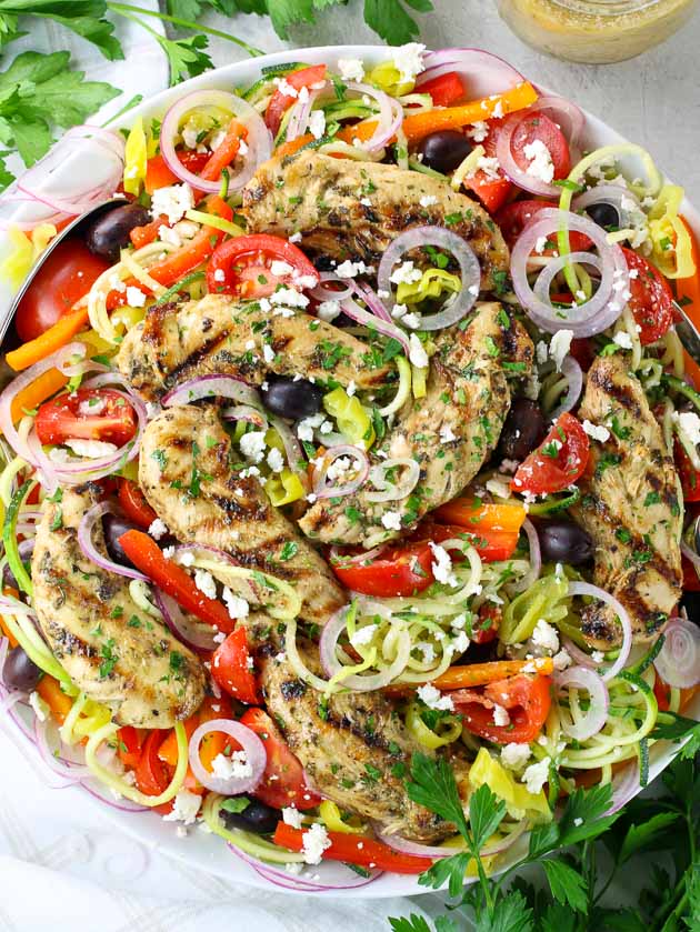 Hearty grilled Greek chicken salad on platter with colorful vegetables