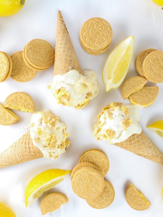 several ice cream cones with lemon cookie ice cream laying on a table with lemon cookies
