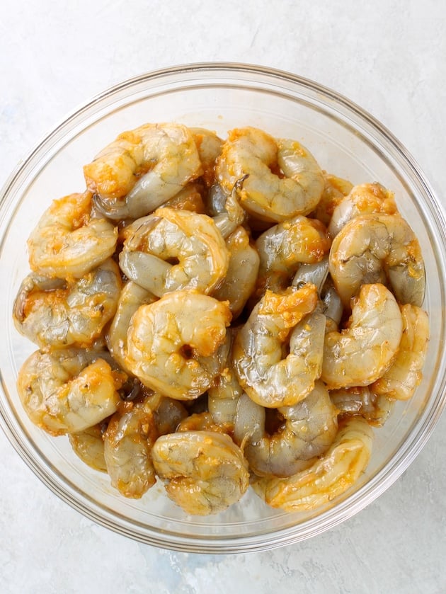 Glass bowl with shrimp coated in buffalo sauce marinade