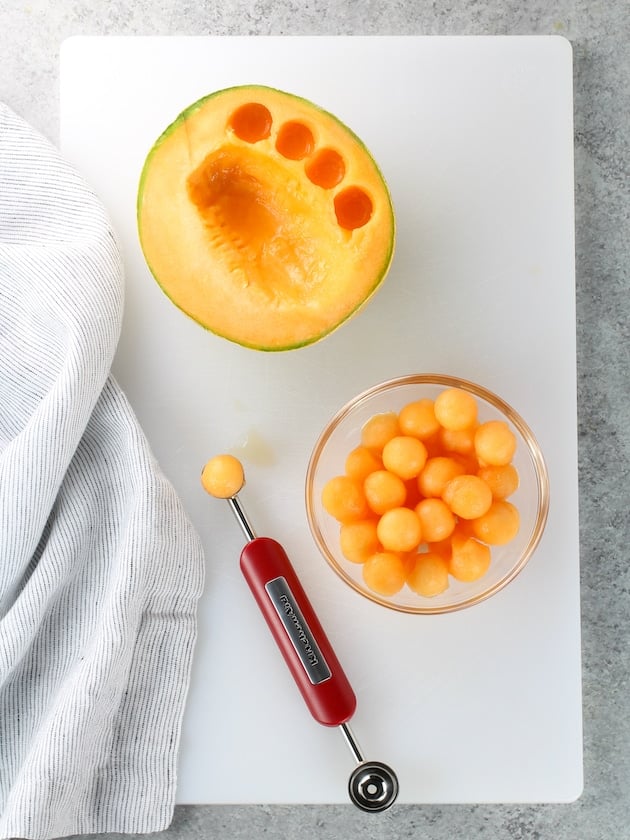 Canteloupe melon balls in a glass bowl on a cutting board - how to make melon balls