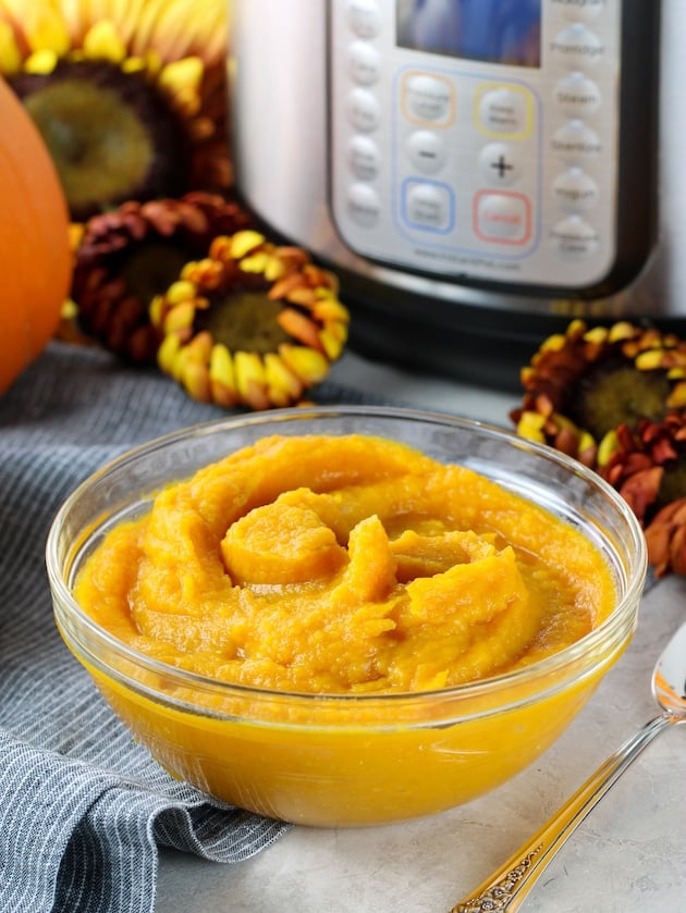 Glass bowl of Homemade pumpkin puree in front of instant po