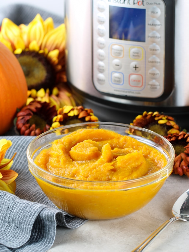Glass bowl of homemade pumpkin puree on table with an instant pot