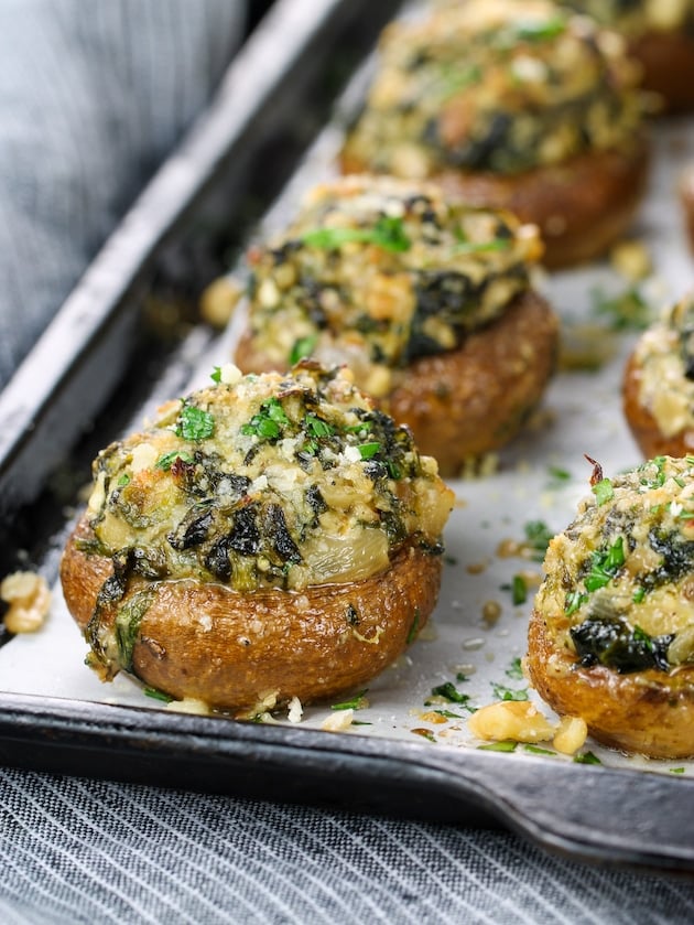 Partial eye level baking sheet of mushrooms stuffed with spinach