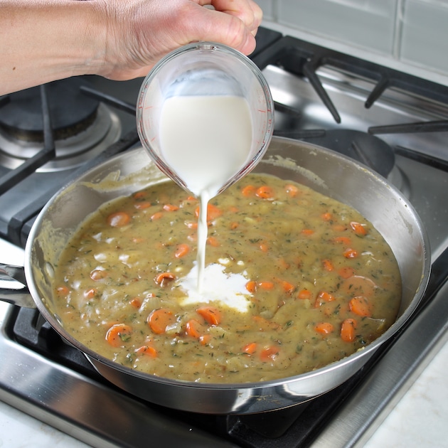 Adding milk to saute pan with carrots, onions, and gravy