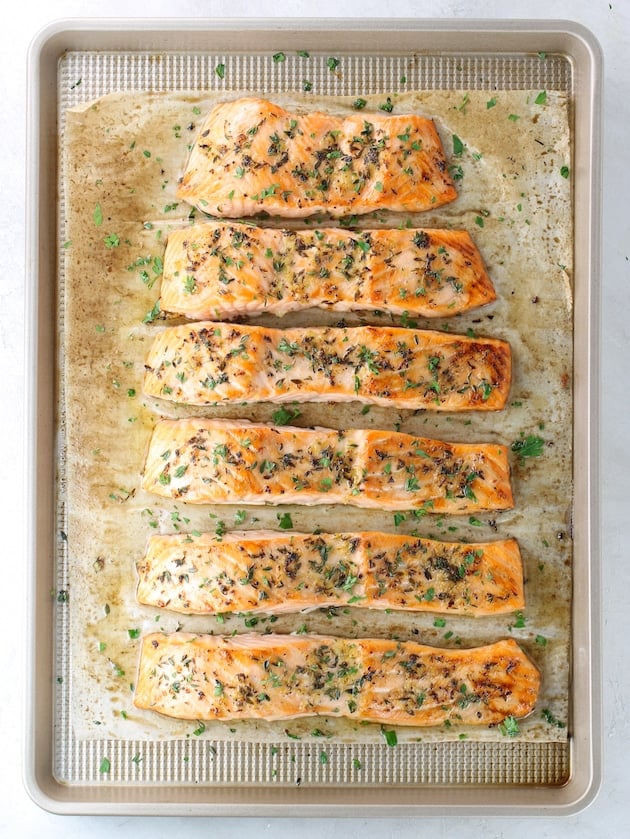 Lemon Pepper Salmon with herbs and garlic on baking sheet after cooking.