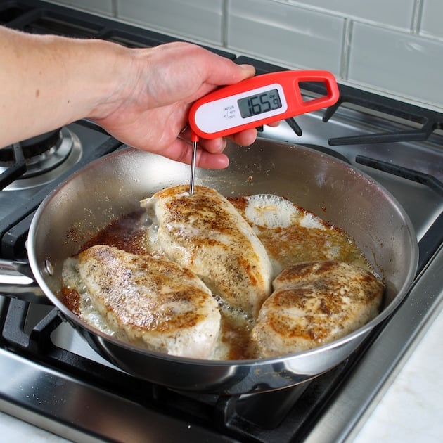 Taking temperature of chicken in saute pan with meat thermometer