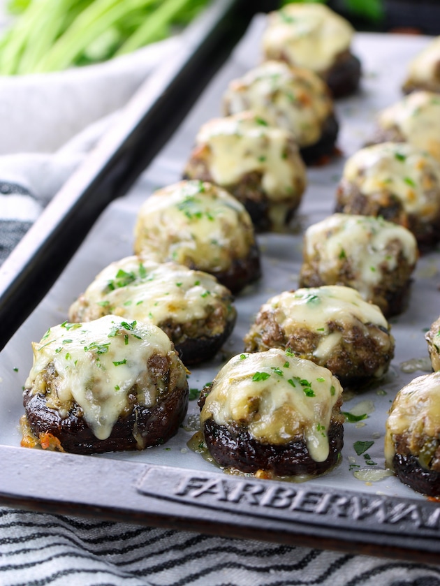 Partial baking sheet of mushrooms topped with melted cheese
