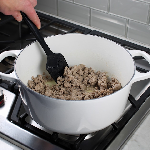 cooking ground turkey in large white soup pot