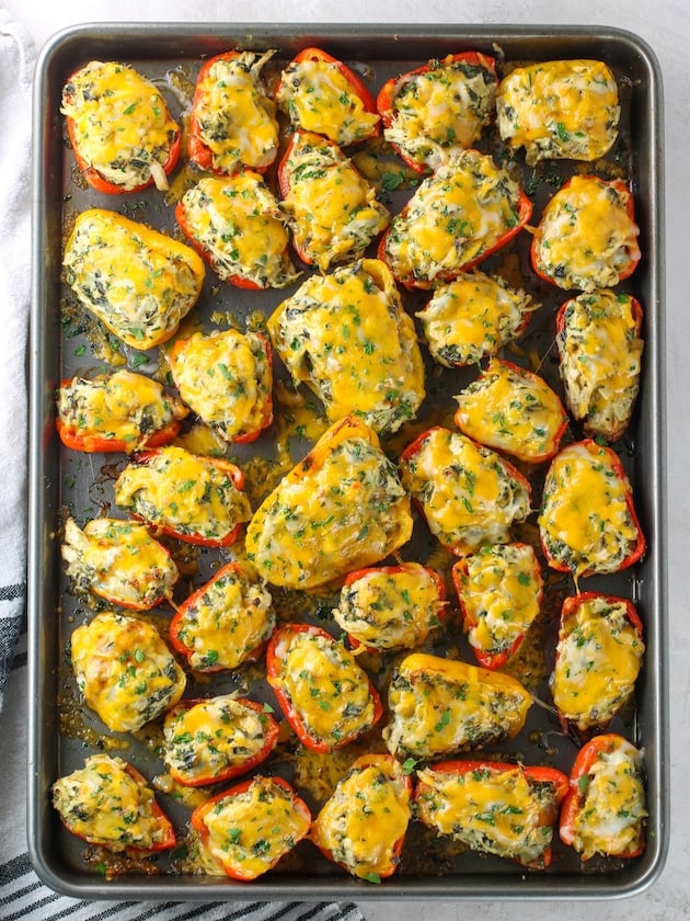 baking sheet of Spinach Artichoke Chicken Stuffed Peppers with melted cheese on top