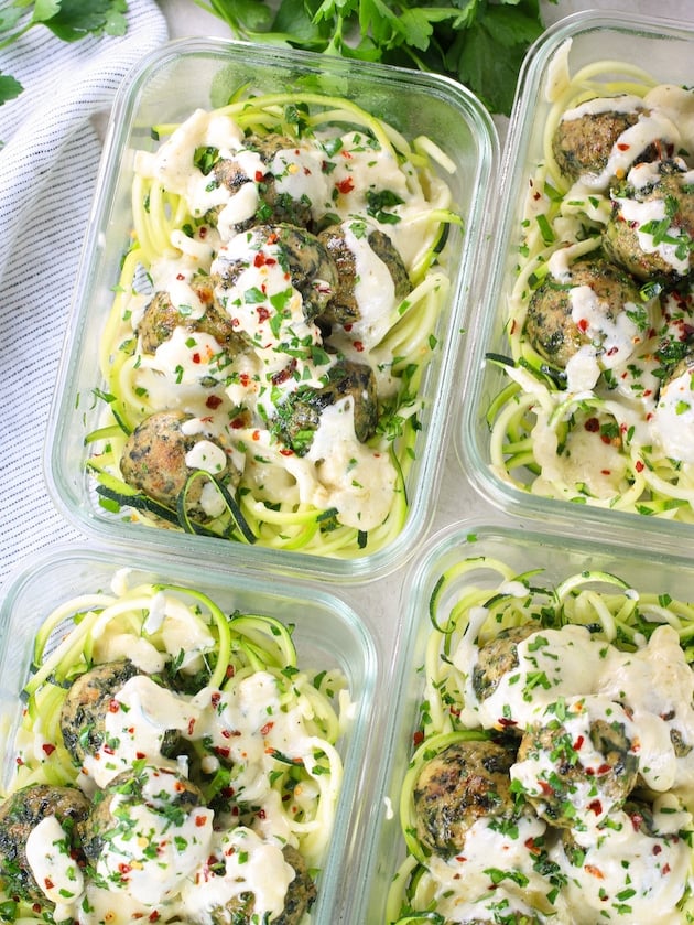 an over the top photo of meatballs with chicken, feta and spinach in meal prep containers