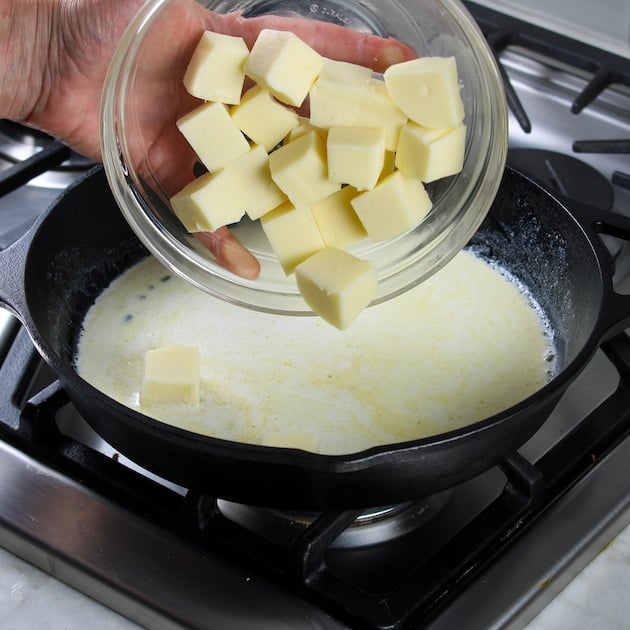 Adding cubes of white cheese to skillet with cream and butter for choripollo