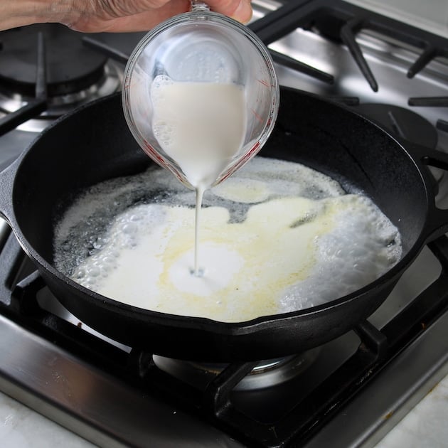 Pouring half and half into skillet with melted butter to make the cheese sauce for the chorizo pollo.