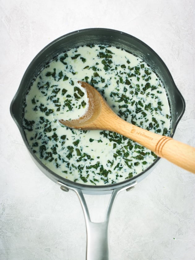 A sauce pan with cream, butter, garlic, herbs and Parmesan cheese.