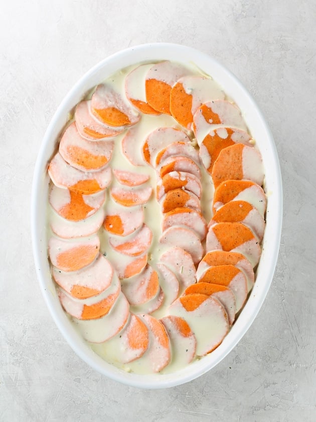 The cream mixture poured over the sliced sweet potatoes arranged in a gratin baking dish with Gruyere cheese.