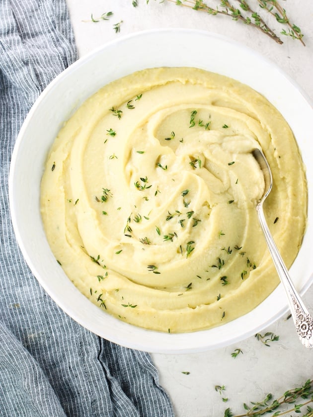 An over the top photos of a bowl of Instant Pot mashed potatoes with herbs sprinkled on top.
