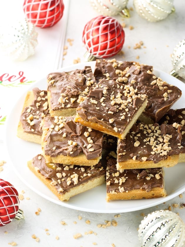Chocolate Caramel Toffee Bars cut up on a plate with Christmas ornaments.