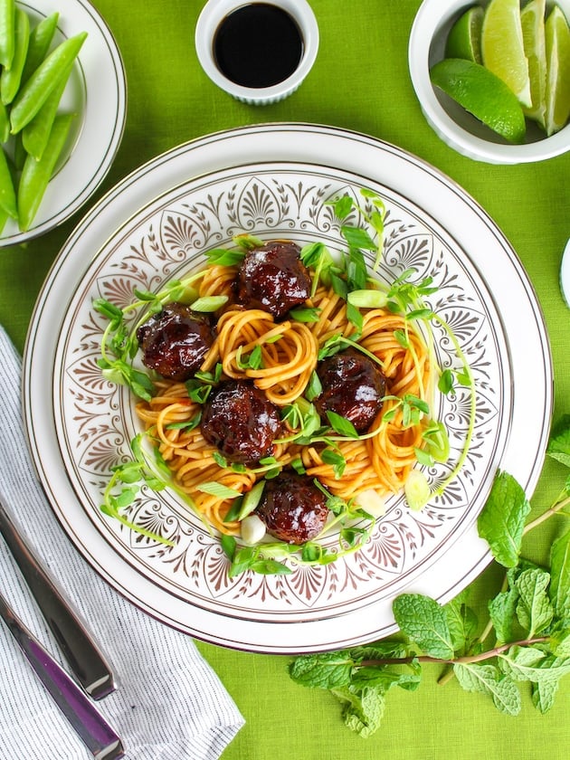Sweet And Tangy Asian Meatballs with noodles on decorative charger plate