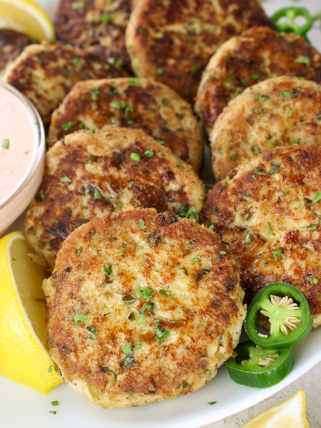 A close up photo of Tuna Cakes on a plate with Sririacha aioli sauce in a bowl next to them.
