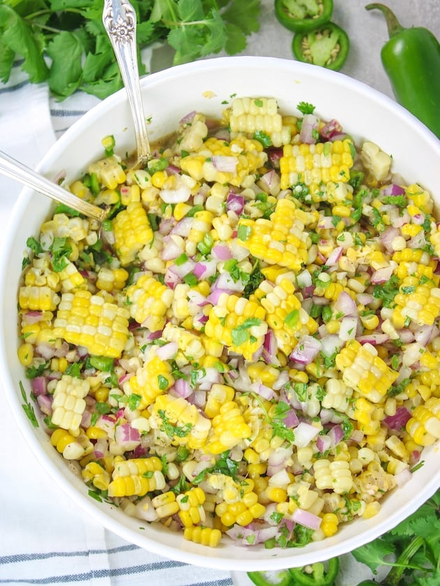 A close up over head photo of Jalapeño Cilantro Corn Salad in a serving dish with spoons