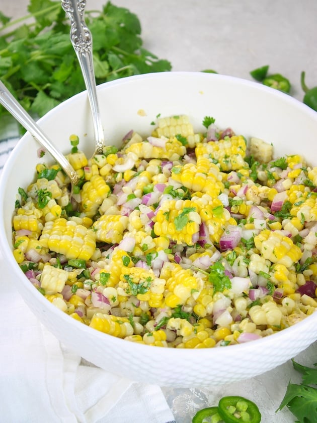 An eye level photo of Jalapeño Corn Salad in a serving dish with spoons