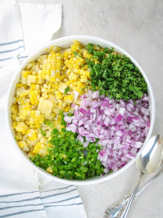 Separate ingredients for the Jalapeño Cilantro Corn Salad in a mixing bowl