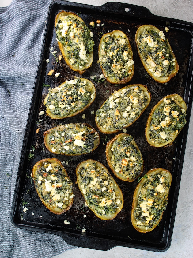 A photo of a whole baking pan with spinach and artichoke baked potatoes.