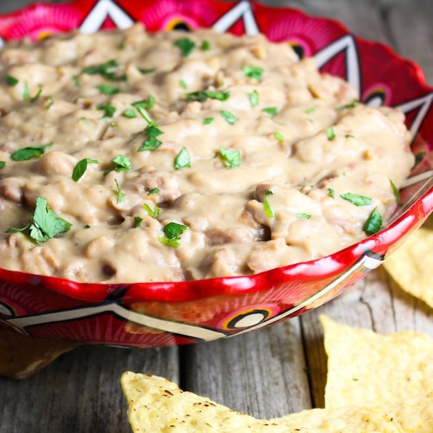 Mexican Refried Beans with cheese in a bowl with corn chips.