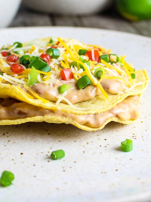 Crunchy Mexican corn tostadas layered with refried beans, shredded cheese, diced tomatoes and green onions