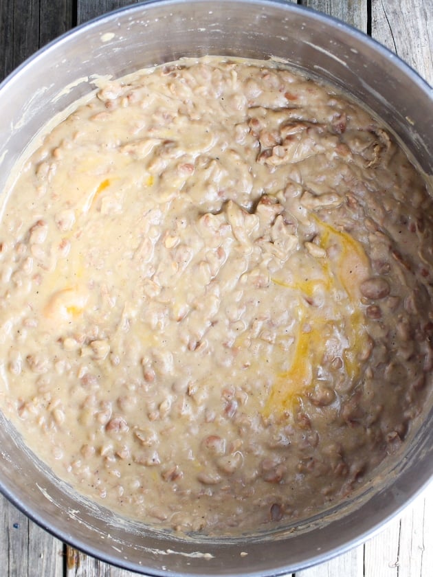 Cooked creamy refried beans with pieces of cheddar cheese stirred in.