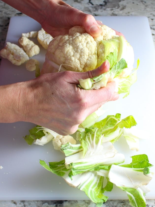 A head of cauliflower with leaves being removed