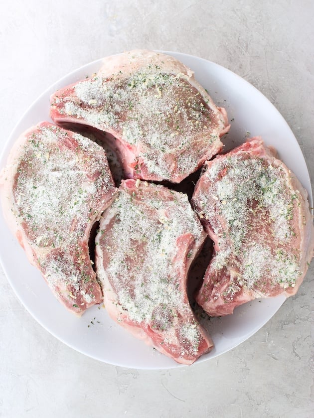 Four raw bone-in pork chops seasoned with a Hidden Valley Ranch Dips Mix packet.