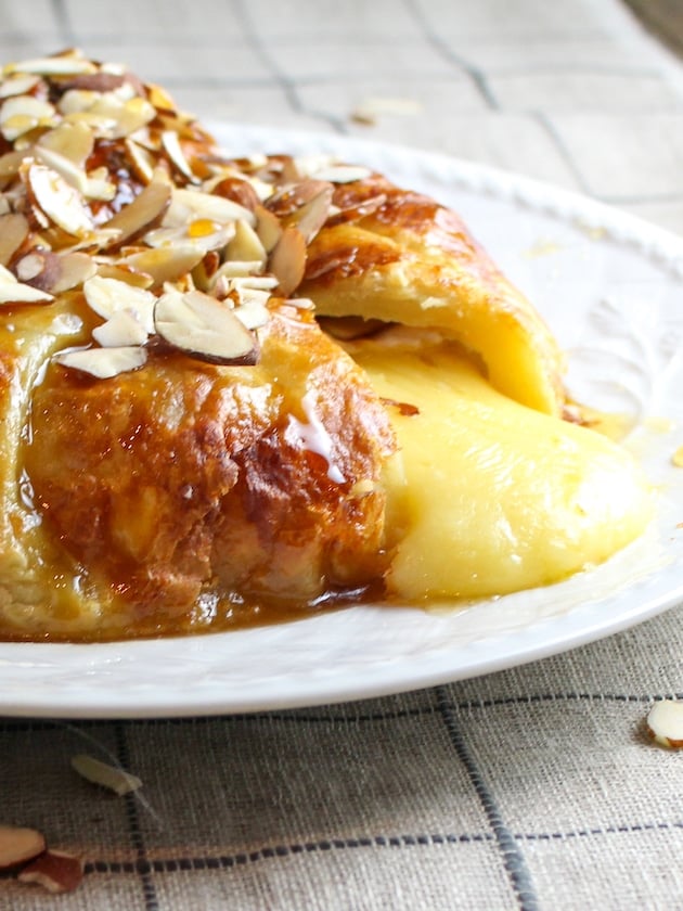 Baked Brie in Puff Pastry with Almonds and Honey cut open with melted cheese running out.