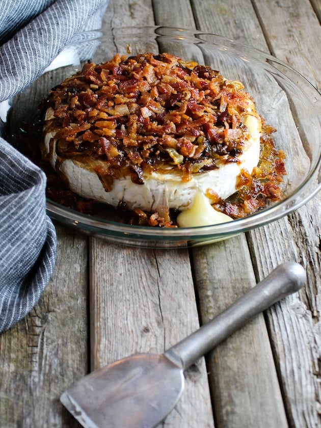 Baked Brie in a pie dish on farm table, with Caramelized Onions and Bacon