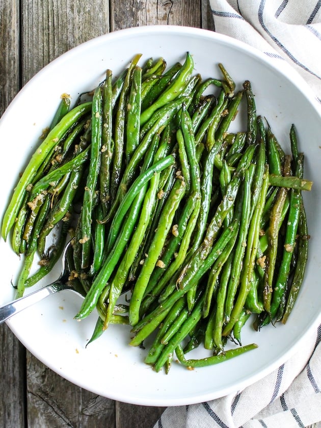 Easy Garlic Green Beans in white china serving bowl, with cloth napkin