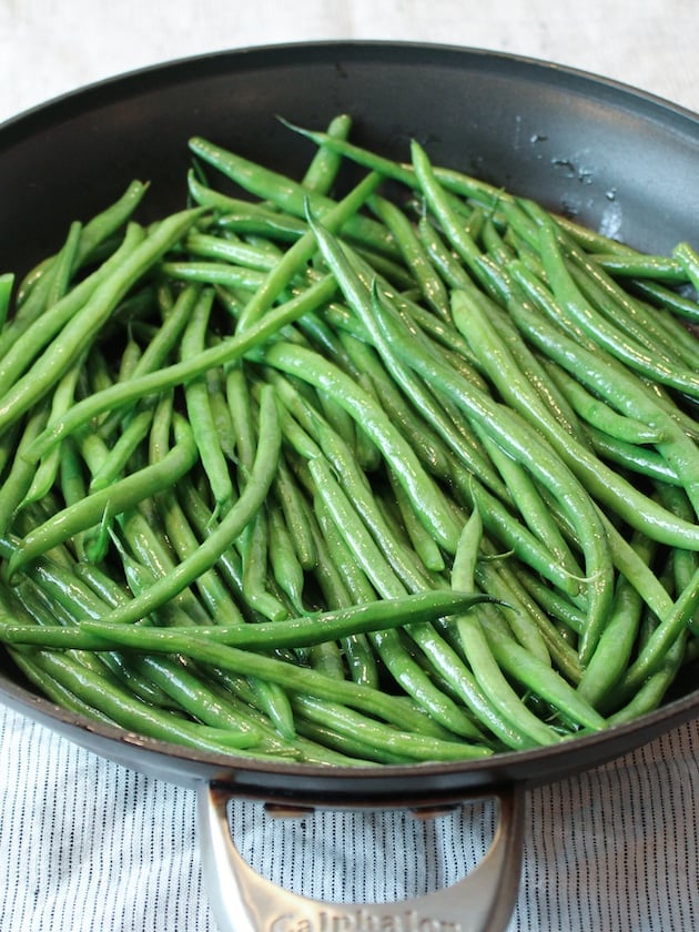 Beans being sautéed in a pan.