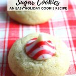 Peppermint Kissed Thumbprint Sugar Cookies sitting on a red and white plaid kitchen towel.